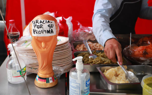 A World Cup trophy replica sits on a street food