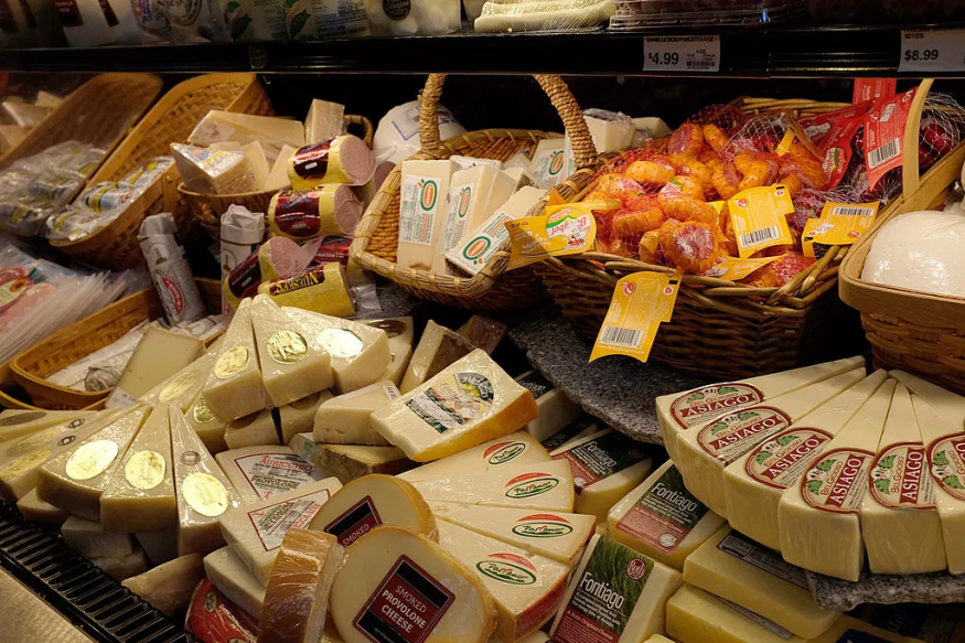 A deli cheese counter displaying various soft and hard cheese